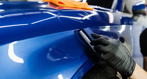 a person using a buffer to polish a blue car