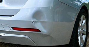 the dented back bumper of a silver car