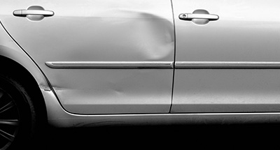 the dented side of a silver car door